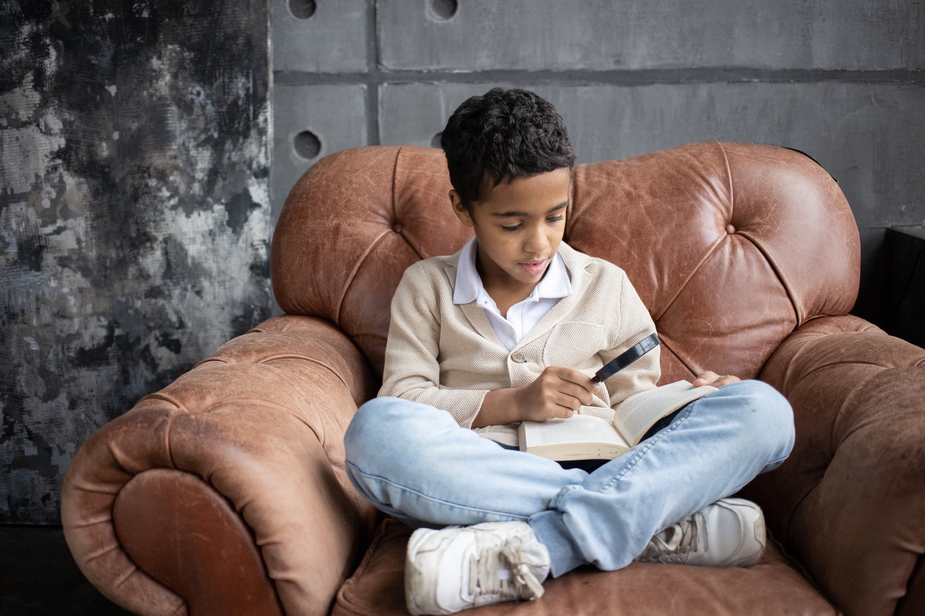 pexels-photo-6186154 focused arabian schoolboy using magnifying glass to read interesting book